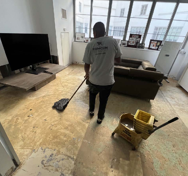 A man is sweeping the floor in his living room.