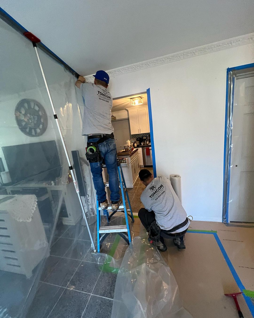 Two men are working on a wall in the house.