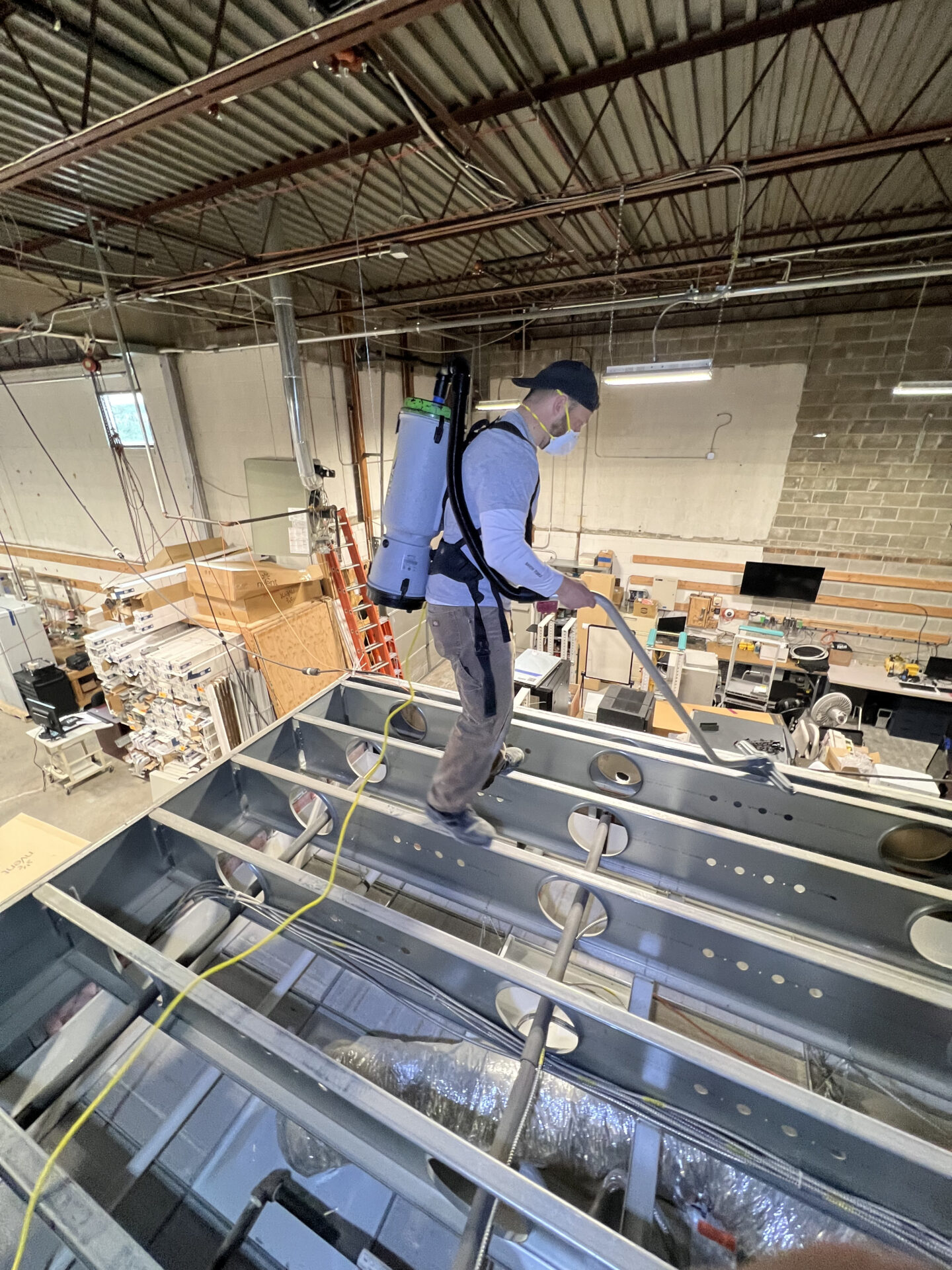 A man in blue shirt standing on top of metal structure.