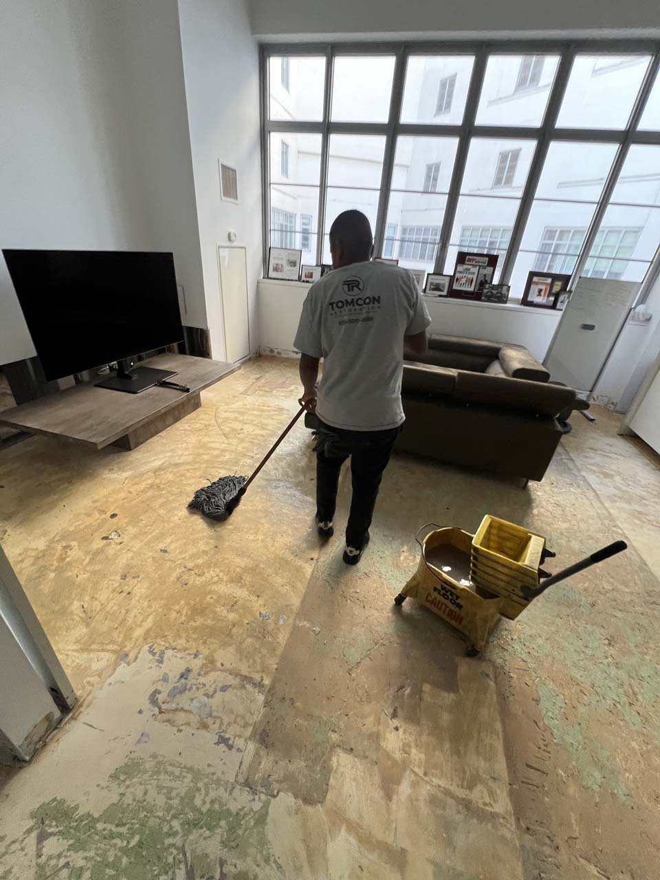 A man is sweeping the floor in his living room.